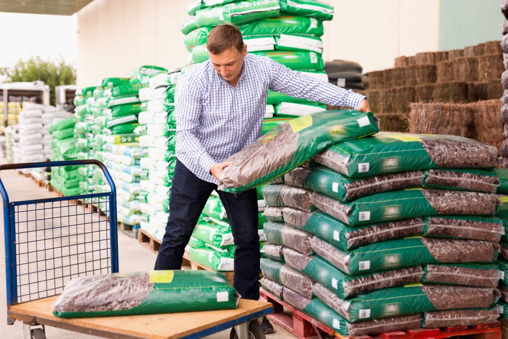 Glad   Man choosing compost soil in plastic bags in hypermarket