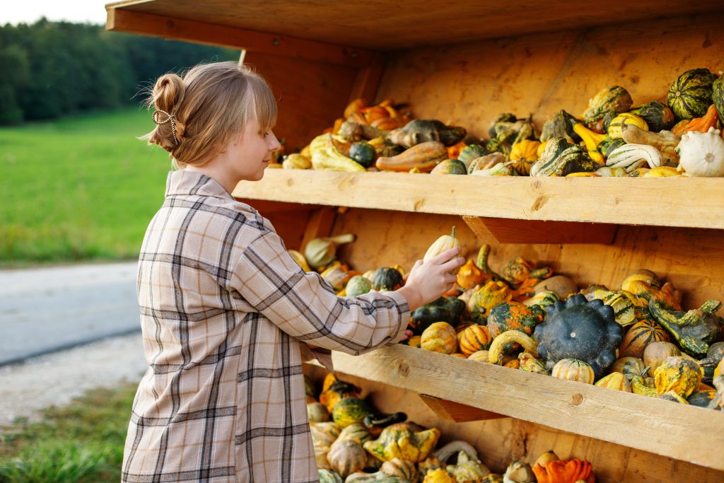 portrait of a woman choosing decorative pumpkins at a local market