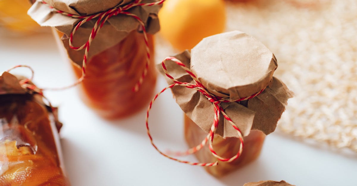a close up image of homemade preserves in jars wrapped with paper and string indoors