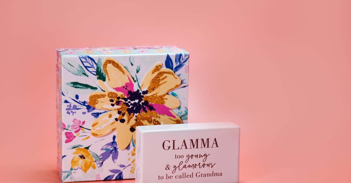 a close up of a floral gift box and a block with the message glamma on a peach background perfect
