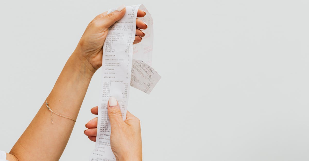 a detailed view of a person holding a long shopping receipt against a plain background 1