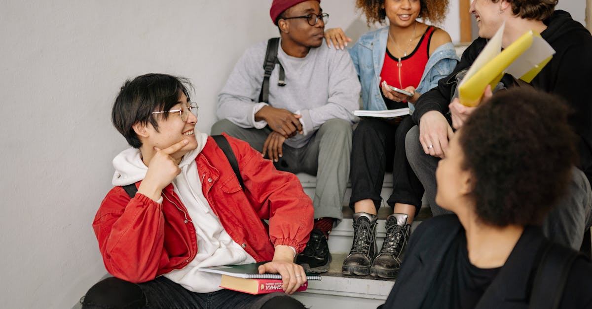 a diverse group of students sitting on stairs smiling and collaborating indoors 1