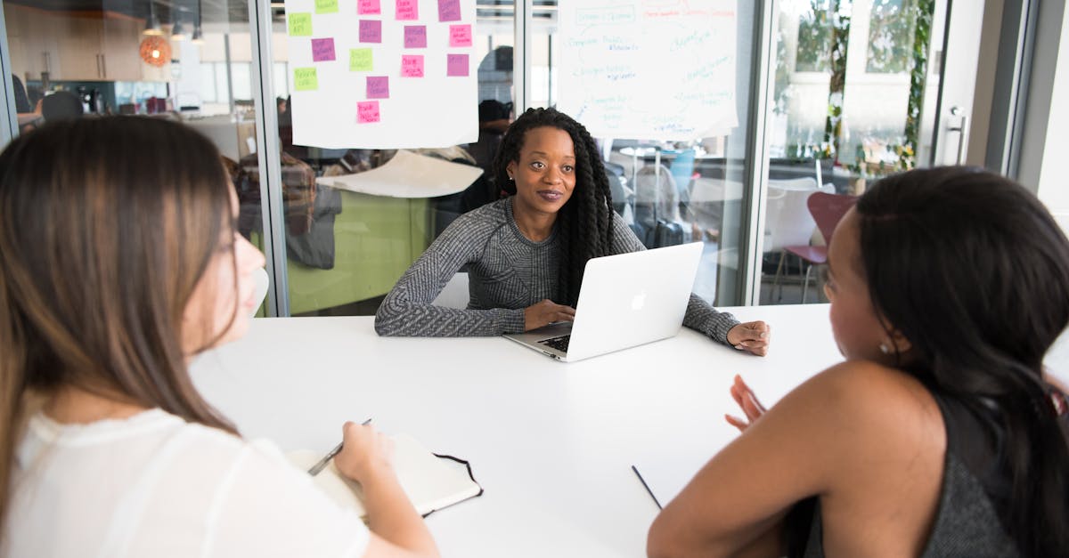 a diverse group of women collaborates around a desk in a modern office setting