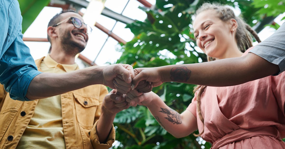 a group of young adults celebrating teamwork with a fist bump in a lush outdoor setting