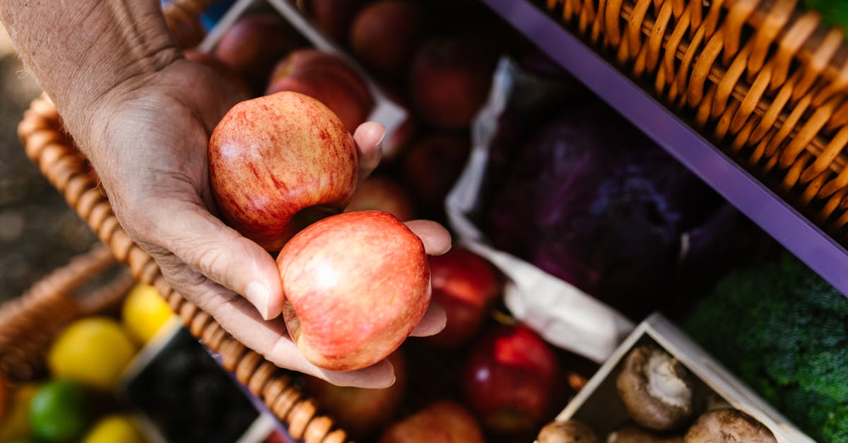 a hand holding fresh apples at a vibrant outdoor farmers market