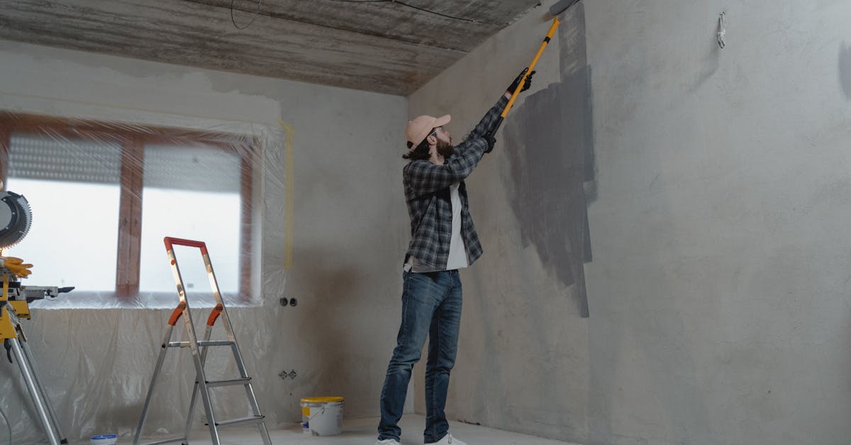 a man painting an interior wall with a roller during a home renovation project 1