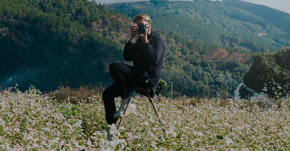 a man takes photographs in a lush field with mountain scenery in the background 4