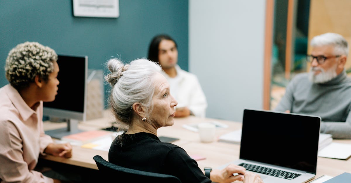 a multicultural team engaged in a meeting around a conference table with laptops