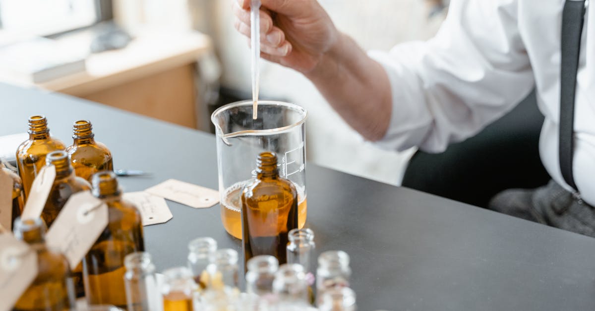 a person blends essential oils in glass bottles for aromatherapy indoors