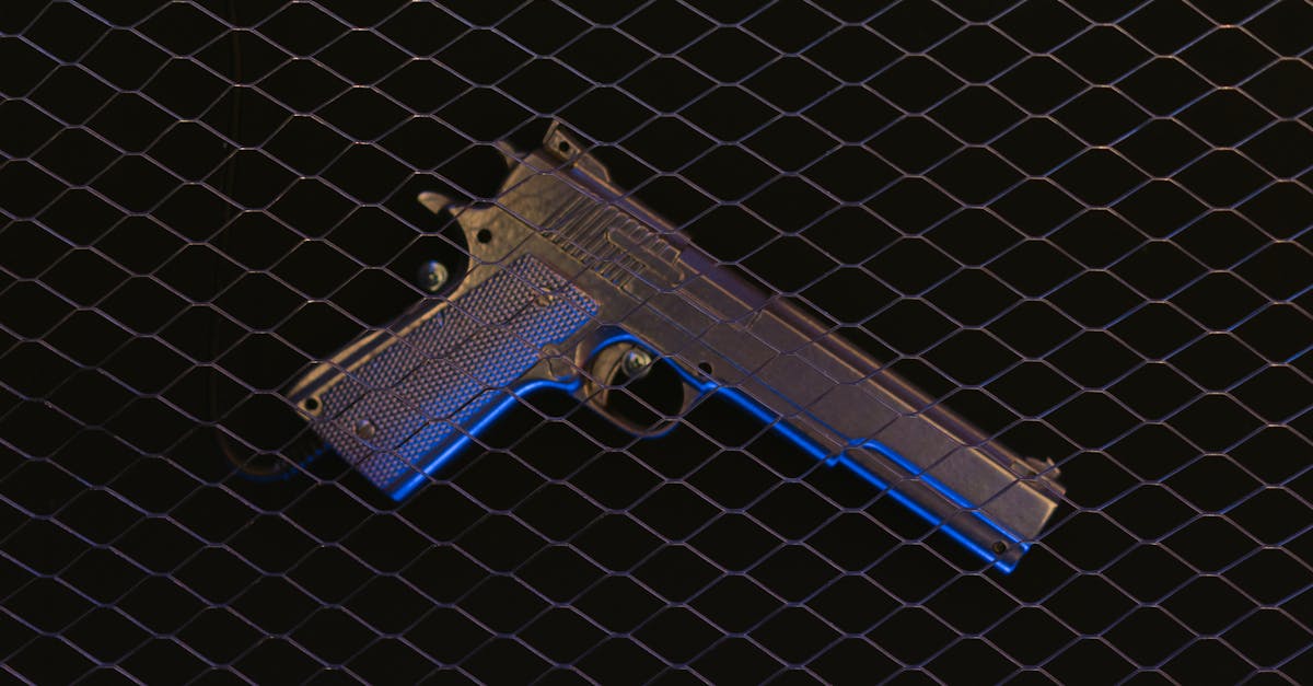 a pistol displayed behind wire mesh illuminated by dramatic blue lighting 1