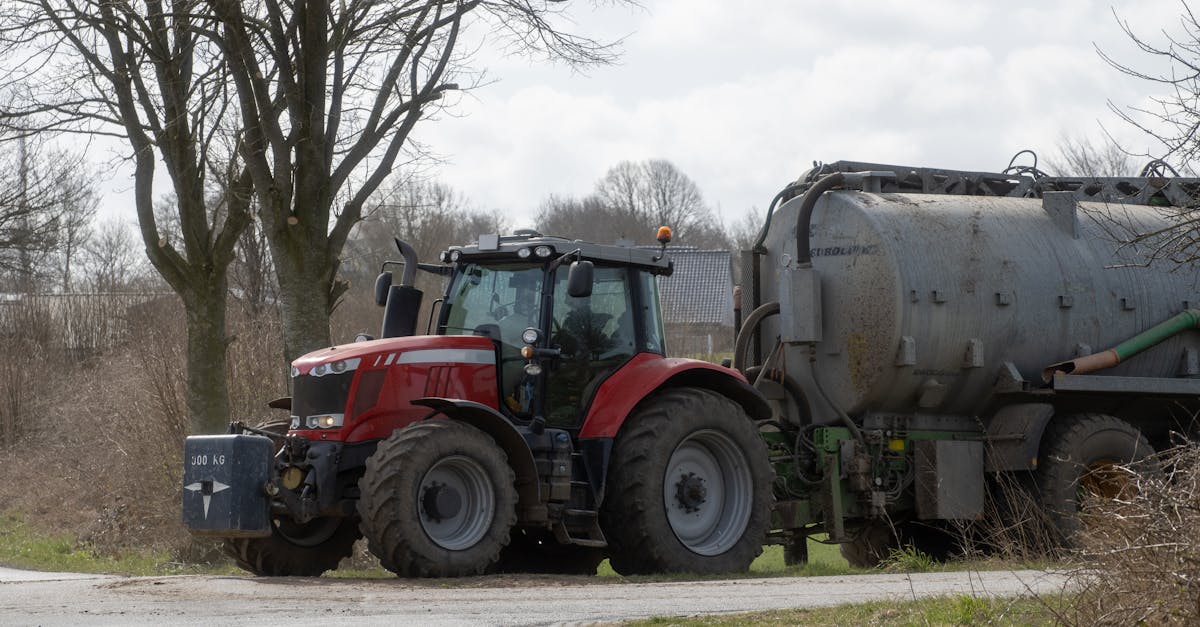 a red tractor with a manure spreader parked on a farm road in springtime rural landscape 3