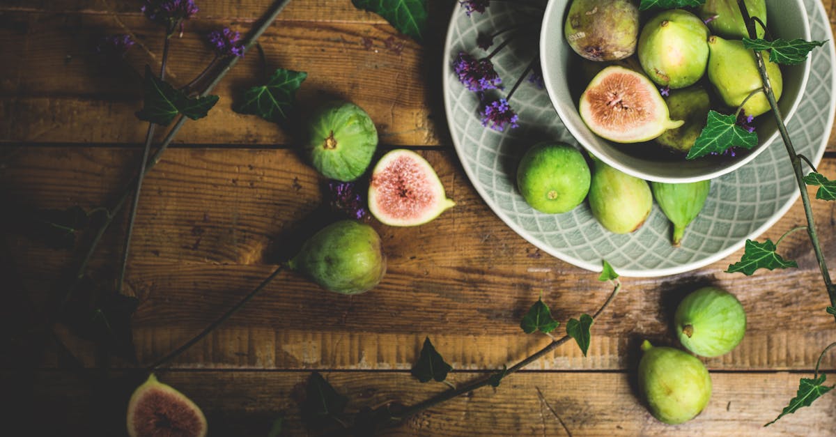 a rustic flat lay of fresh green figs in a bowl on a wooden table complemented by ivy leaves