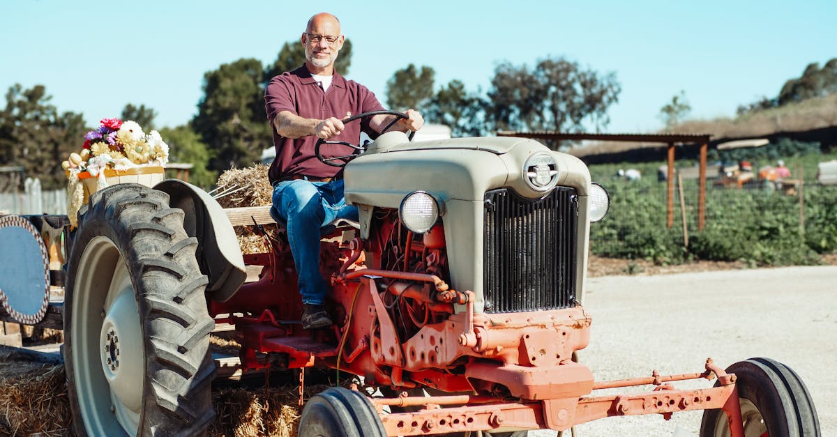 a smiling bald man drives a vintage tractor on a sunny farm day surrounded by summer scenery 4