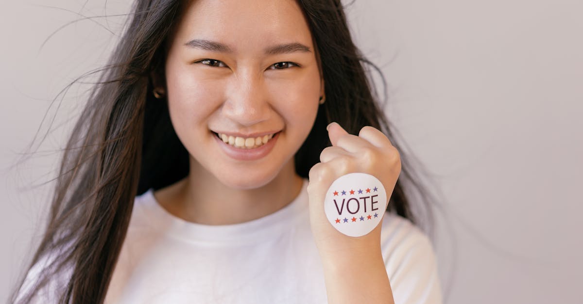 a smiling young woman holds up a vote sticker promoting the spirit of democracy and participation