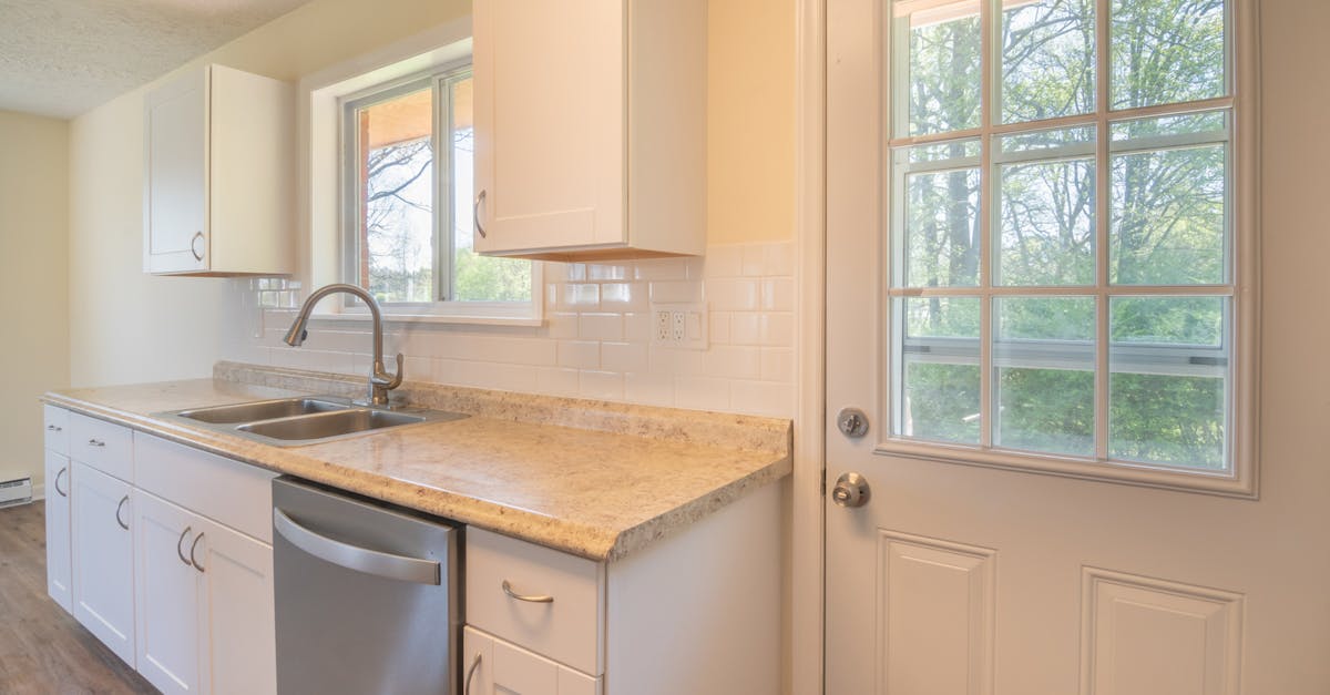 a sunlit modern kitchen with white cabinets a sink and a window view 1