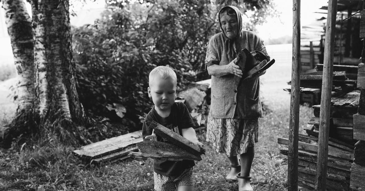 a touching black and white scene of a grandmother with her grandson gathering firewood outdoors 3