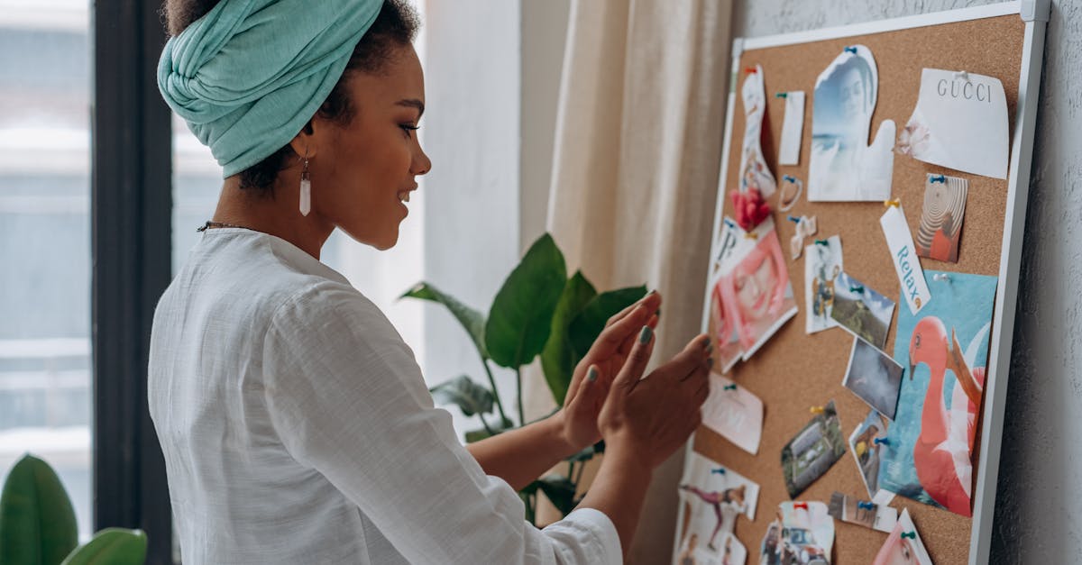 a woman arranging a creative mood board with diverse images and notes in a stylish interior