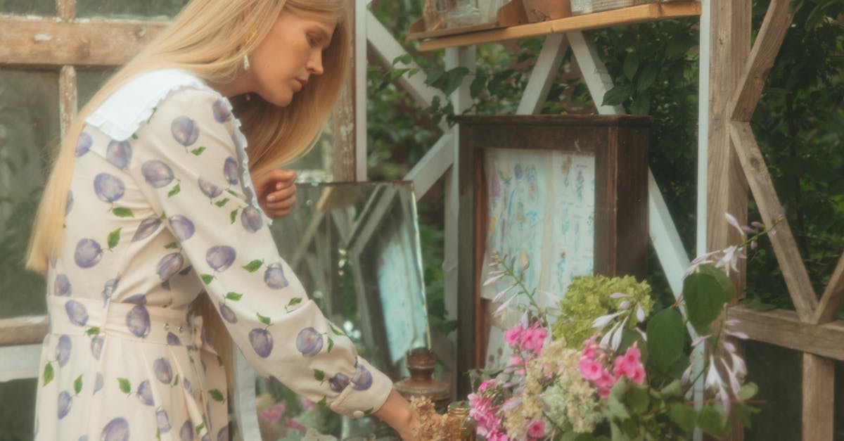 a woman in a floral dress arranges flowers in a charming rustic garden shed