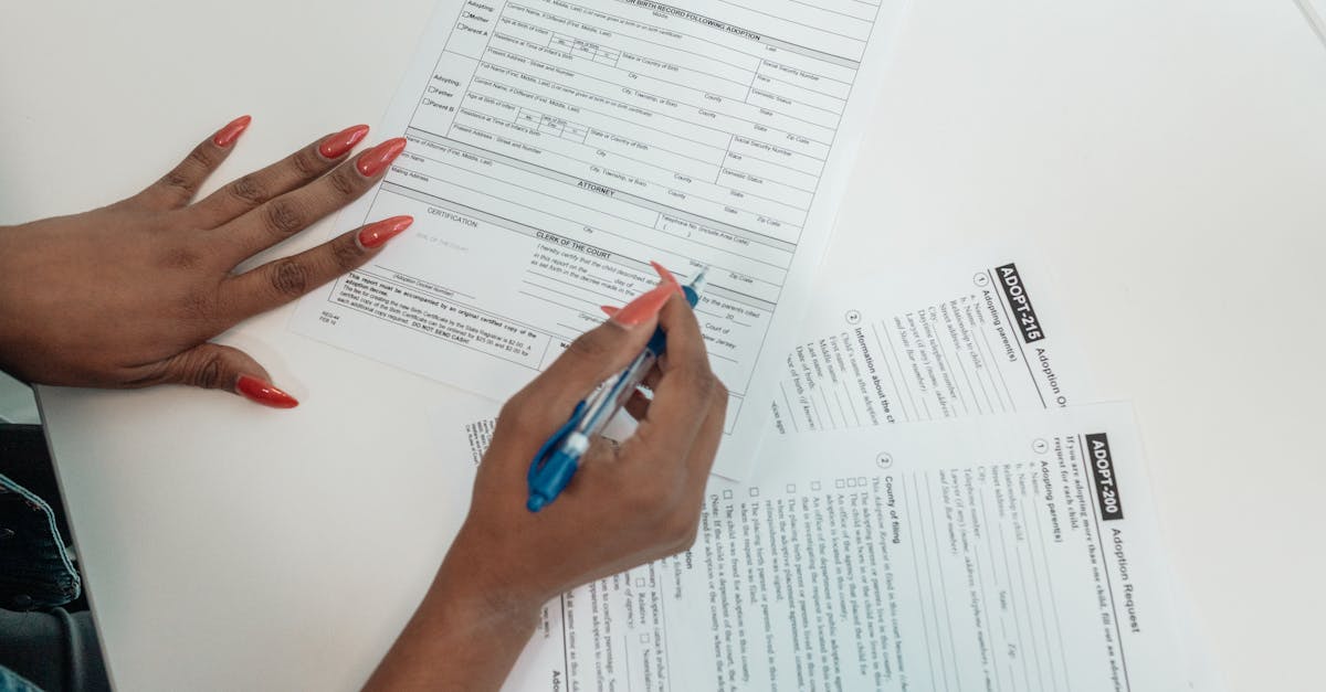 a woman with red nails fills out adoption application forms on a desk