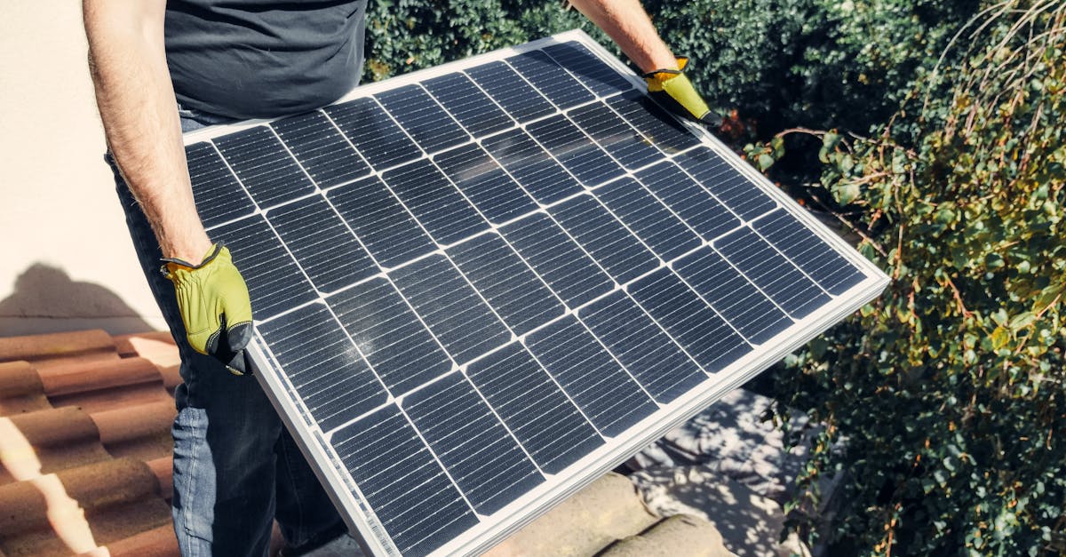 a worker in gloves installs a solar panel on a tiled rooftop promoting renewable energy