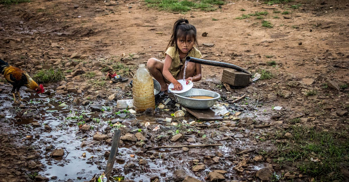 a young girl washes dishes at an outdoor hand pump reflecting rural daily life 3