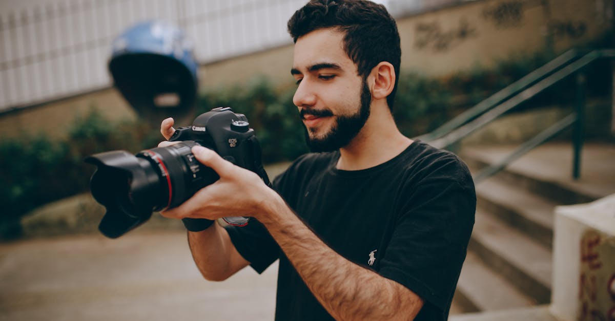 a young man focusing a dslr camera outdoors preparing for a photoshoot