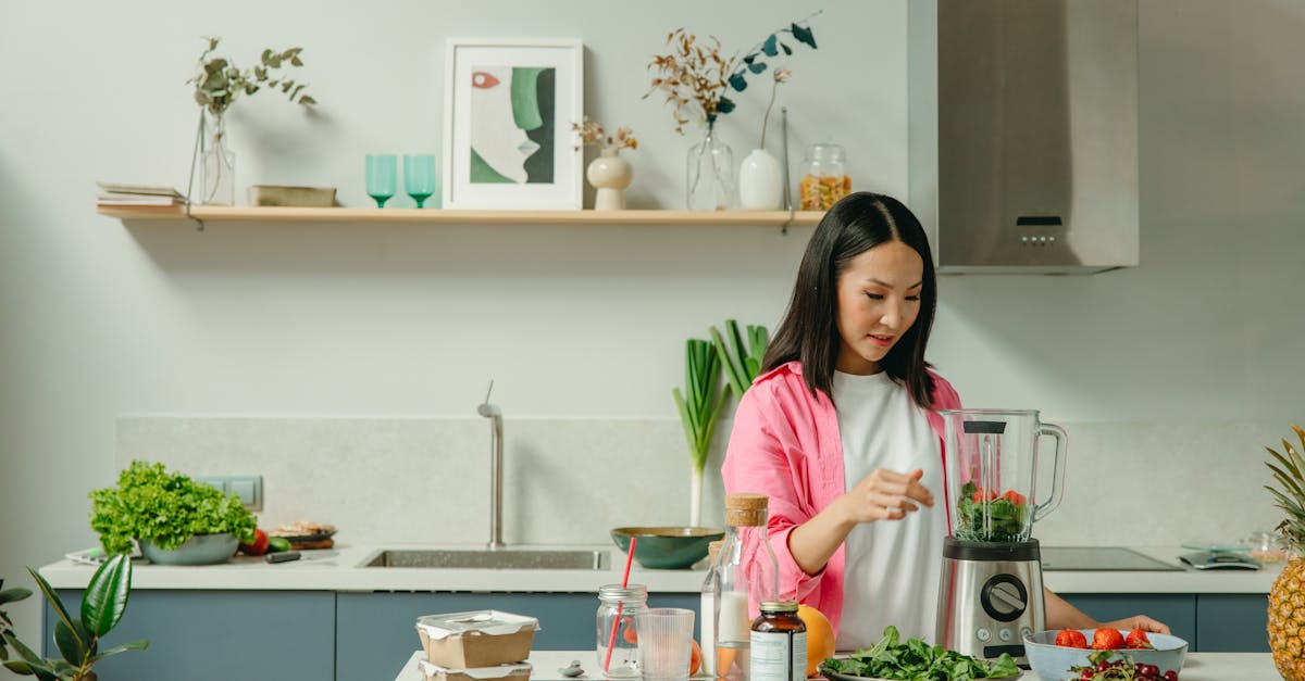 asian woman blending fresh fruits and vegetables in a stylish kitchen setting