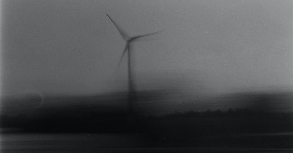 blurred black and white image capturing the motion of a solitary wind turbine creating an eerie fee
