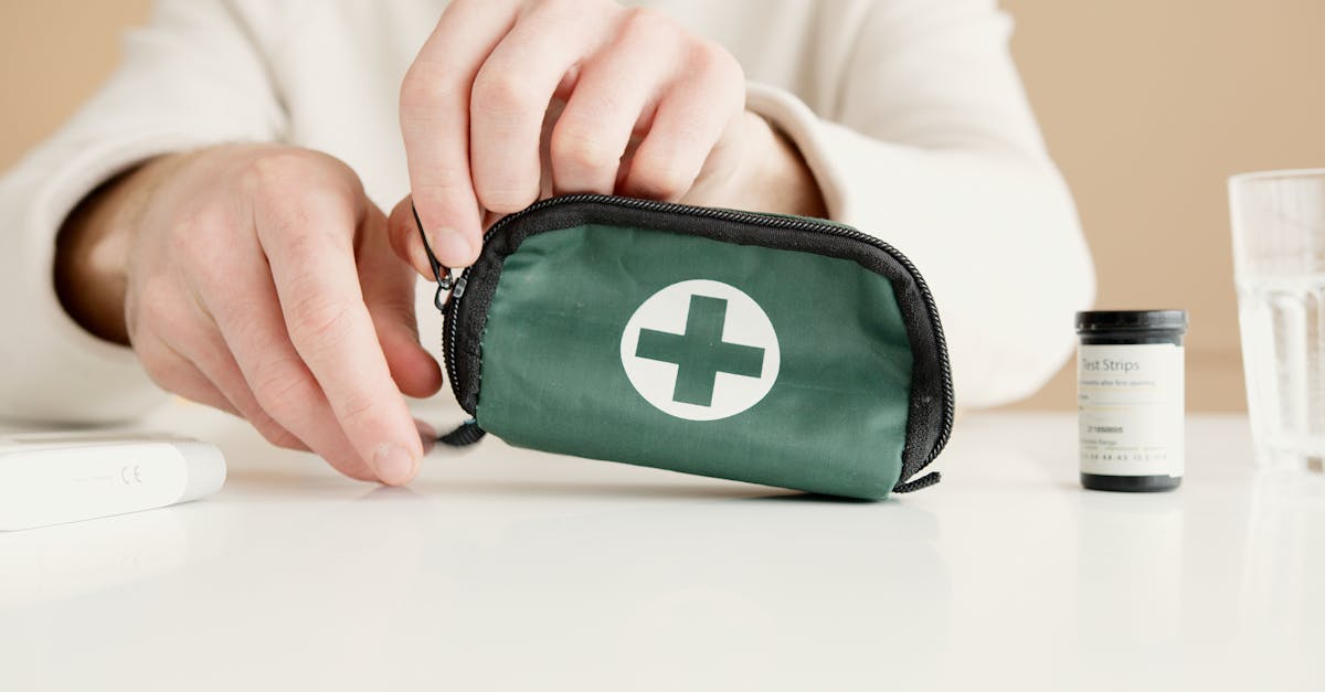 close up image of hands holding a first aid pouch on a table with medical test strips nearby