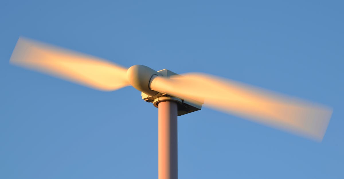 close up of a spinning wind turbine against a clear blue sky symbolizing renewable energy
