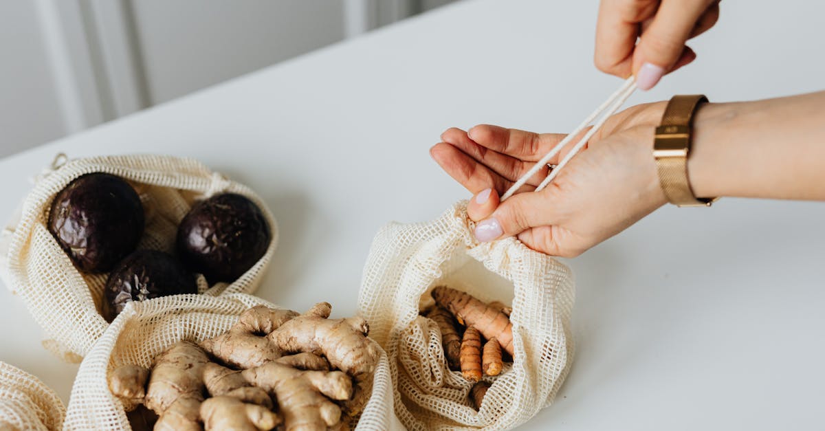 close up of hands using eco friendly mesh bags filled with fresh ginger and avocados