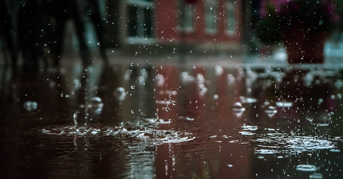 close up of raindrops splashing into a puddle capturing reflections and textures in an outdoor urba