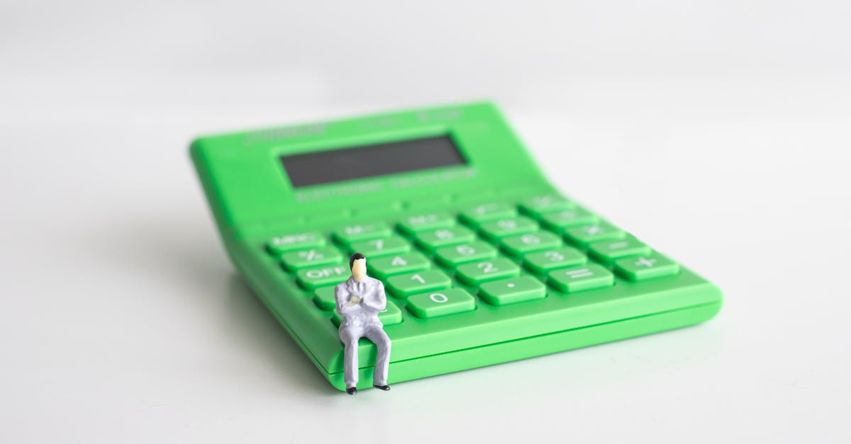 conceptual image of a miniature businessman sitting on a green calculator symbolizing finance and c 2