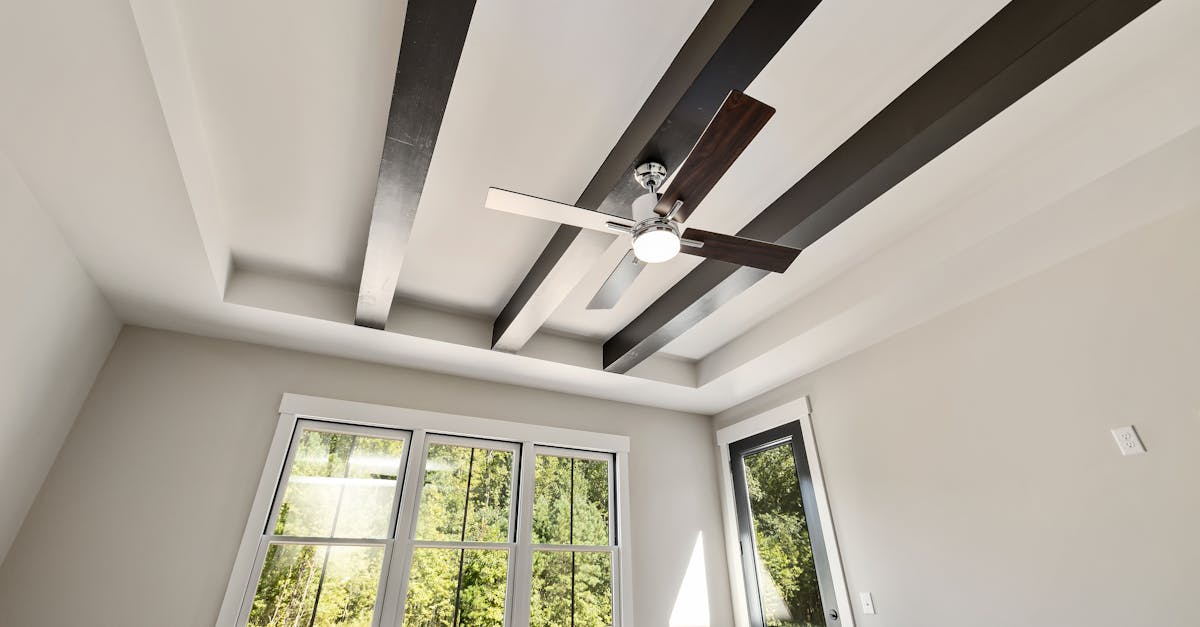 contemporary room featuring a ceiling fan exposed beams and large windows