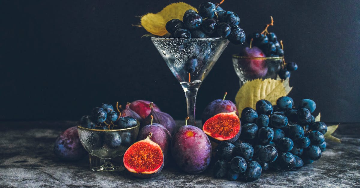 dark moody still life of fresh grapes and figs in a glass setting highlighting autumn flavors