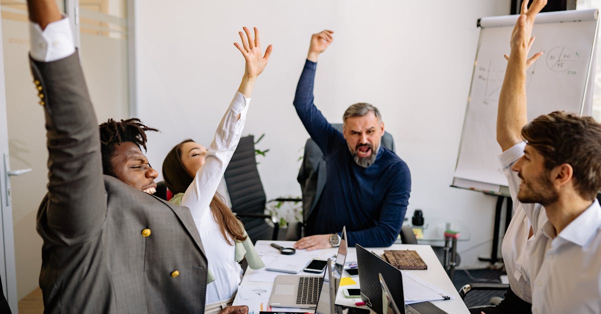 diverse business team raising hands in excitement during a meeting in a modern office