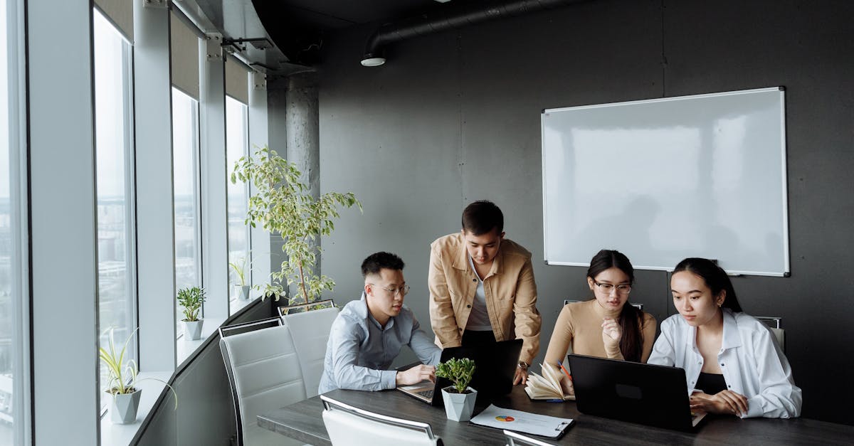 diverse group of professionals collaborating around laptops in a modern office setting