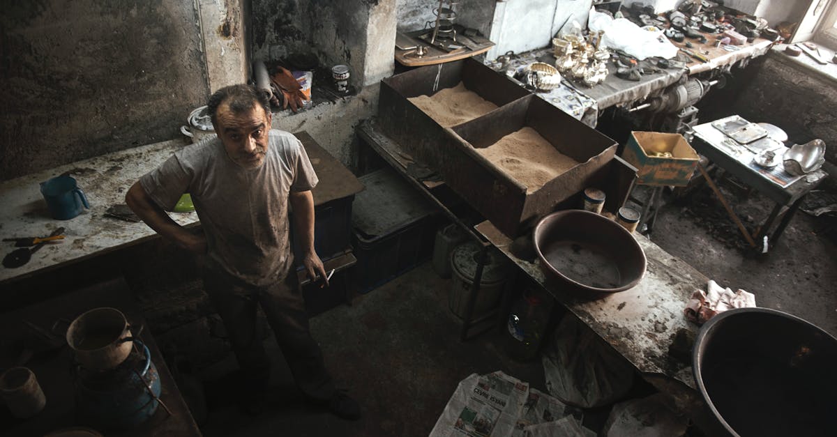 elderly man standing in a cluttered rustic workshop with tools and materials