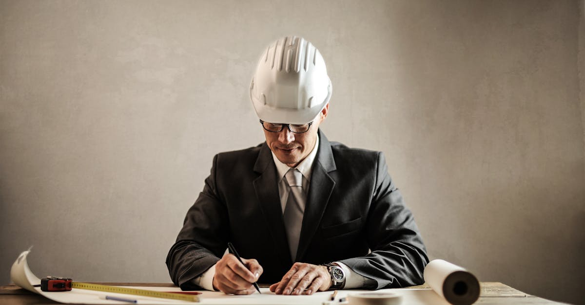 engineer in a suit drafting architectural plans at a desk indoors