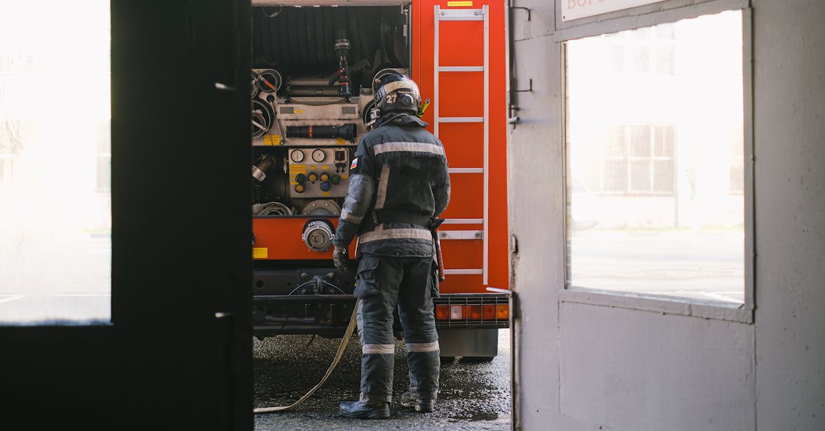 firefighter preparing equipment at fire engine near station entrance safety and emergency readiness