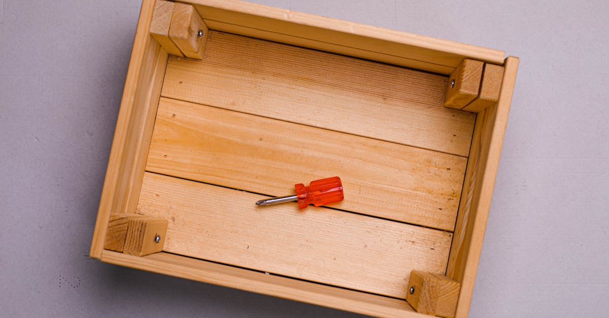 flat lay of a red screwdriver inside an empty wooden box on a gray background