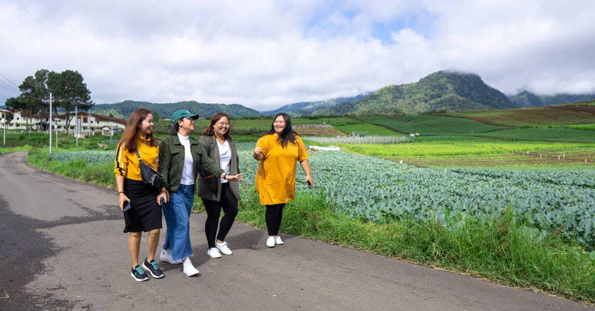 four friends walking and laughing along a rural road in batu east java with scenic farmland and mo