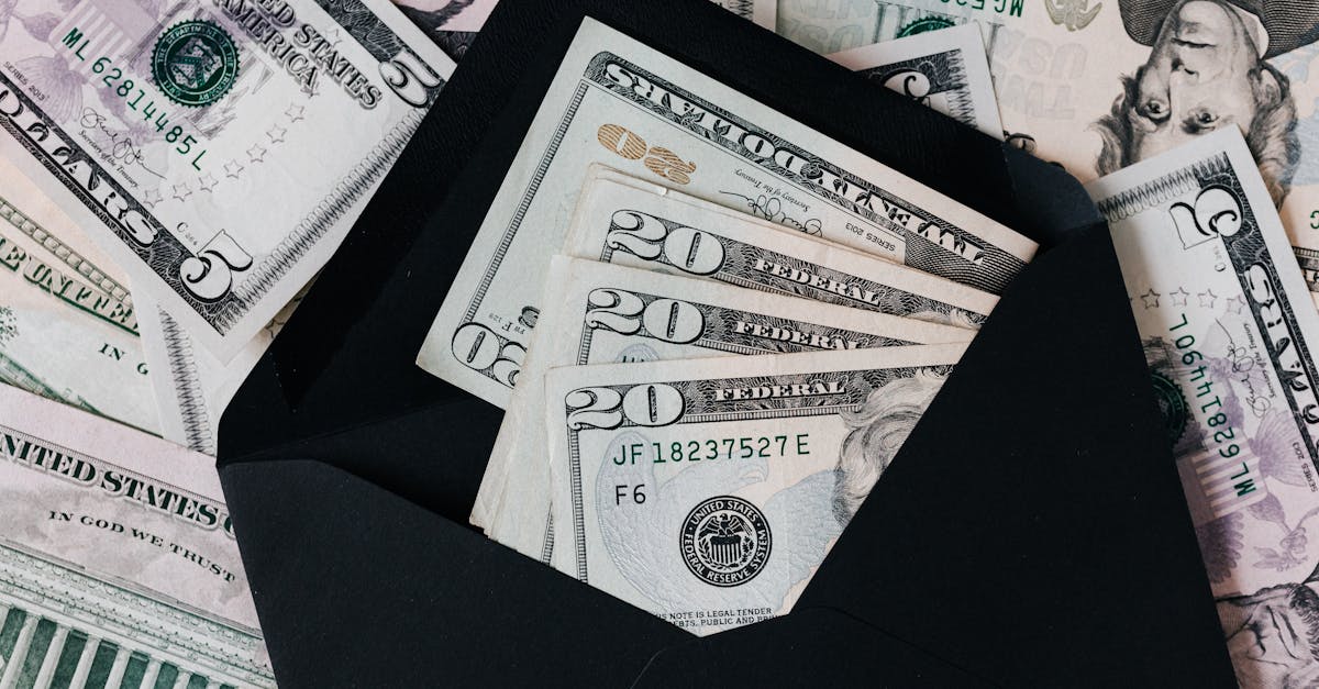 from above of dollar bills in opened black envelope placed on stack of united states cash money as c