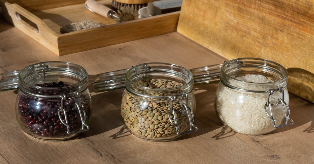 glass jars of beans lentils and uncooked rice on a wooden table with warm lighting