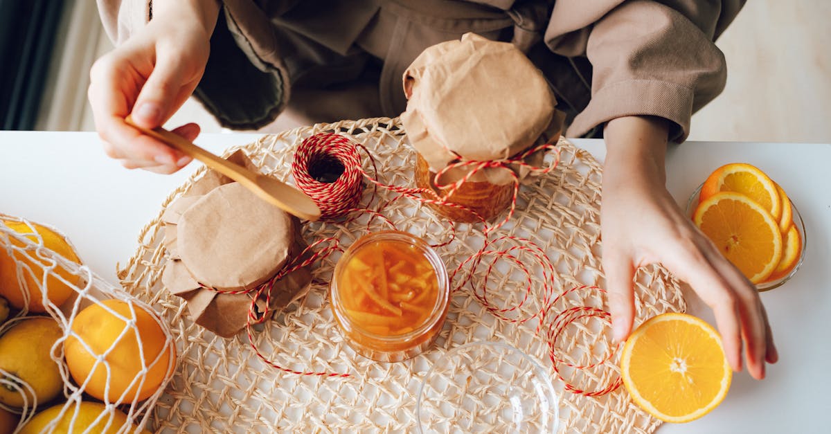 hands preparing homemade orange marmalade with fresh oranges and jars