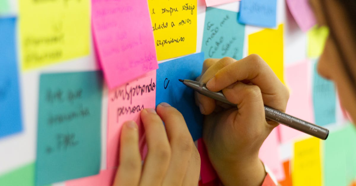 hands writing on colorful sticky notes during a brainstorming session indoors