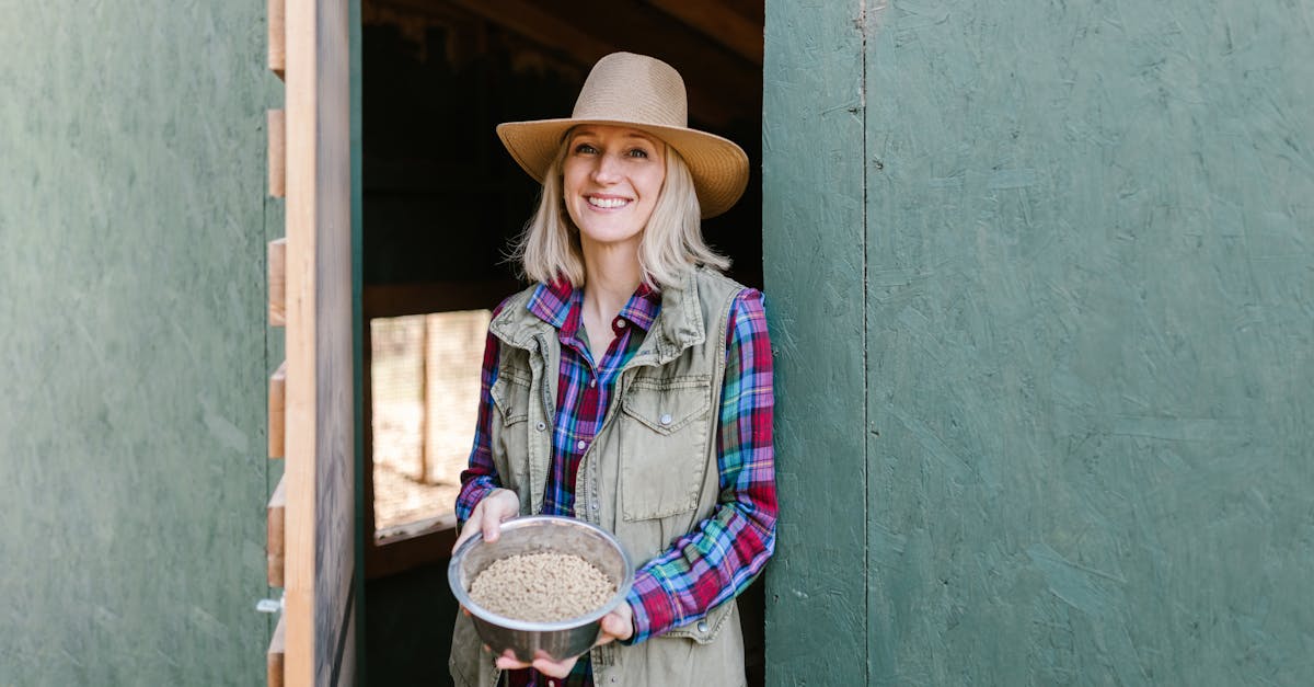 happy female farmer with hat holding feed bowl at ranch door 3