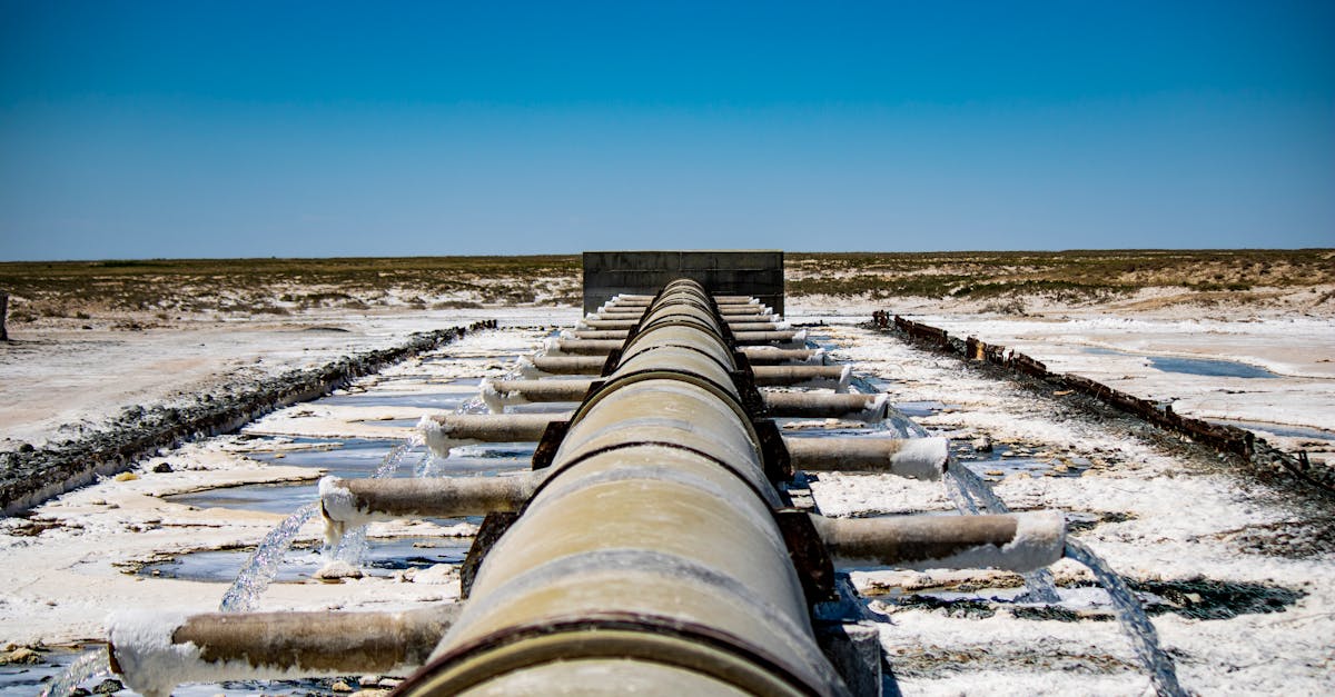 large industrial pipeline discharging wastewater in arid rural landscape under clear blue sky