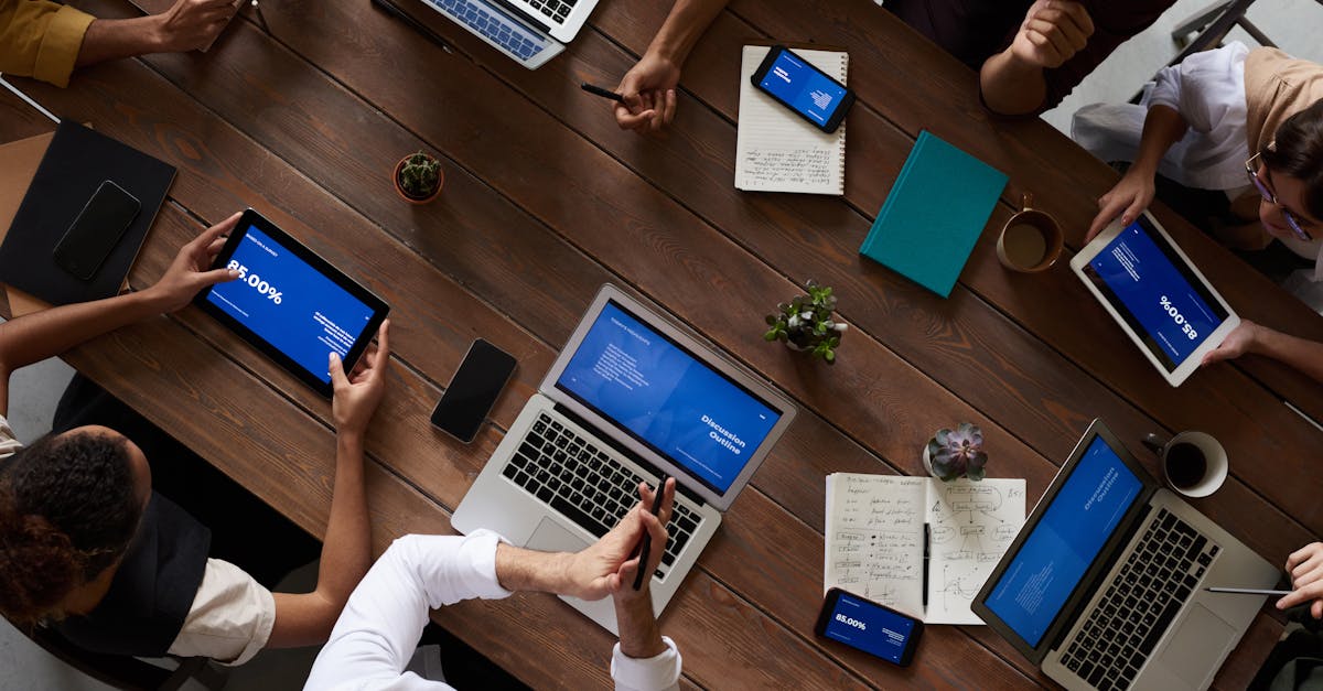 overhead view of a diverse team discussing around a wooden table using technology 2