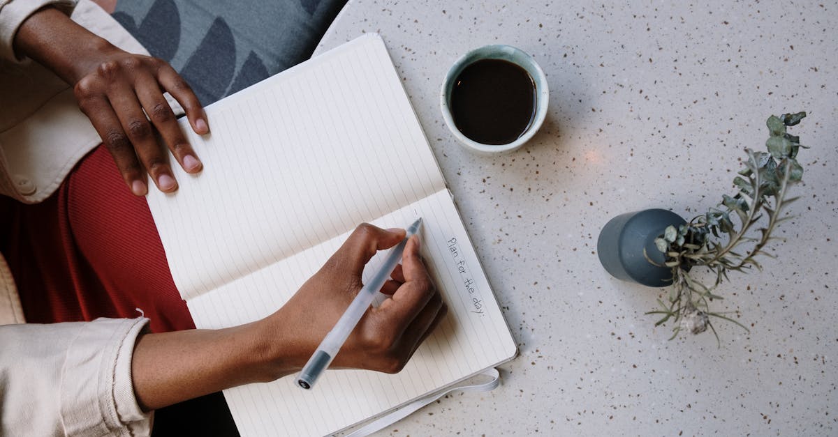 person writing in a planner with coffee at a cafe focusing on planning and productivity